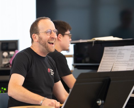 A man smiling whilst sat at a piano.